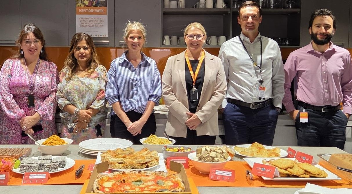 Six LSA staff smiling and standing behind a table full of food.