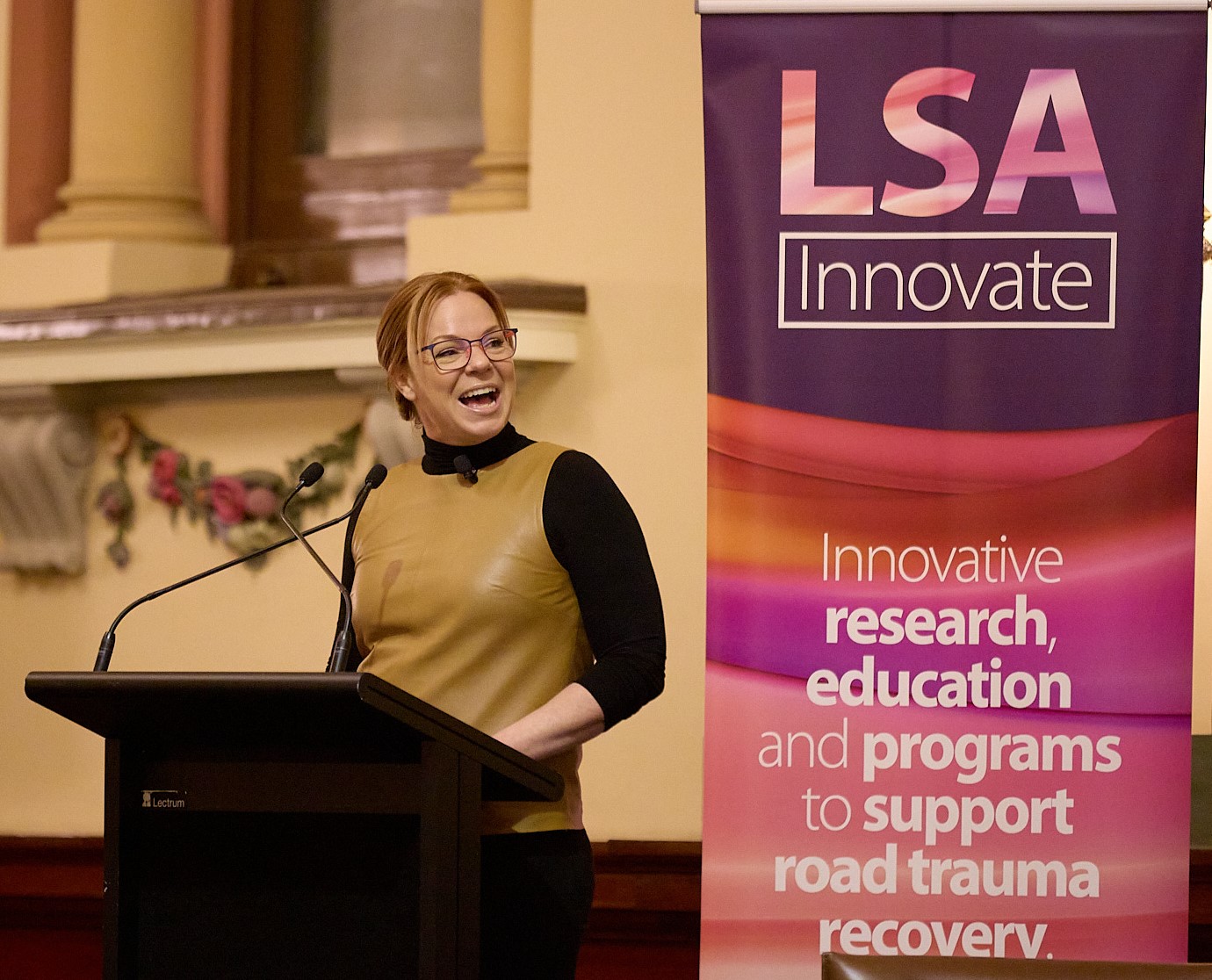 Woman speaking at a lectern in front of a LSA Innovate banner