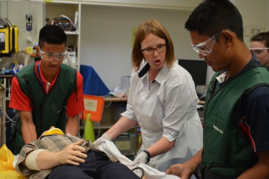 Nurse instructs students to move an injured mannequin.
